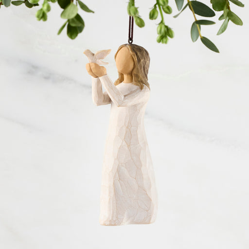 Decorative angel figurine holding a dove with greenery in the background