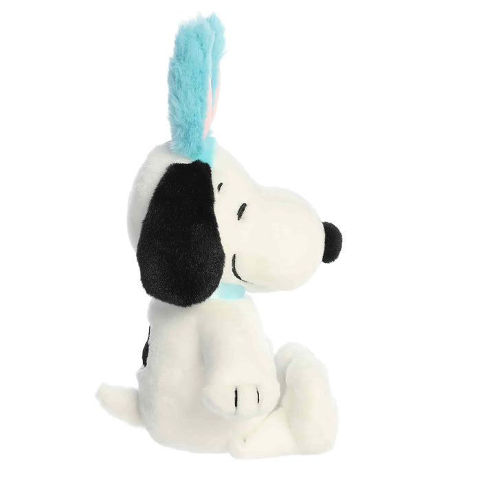 Plush toy of a dog with a blue feather on a white background