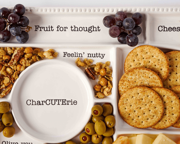 Charcuterie board with various food items including grapes, nuts, crackers, and olives.