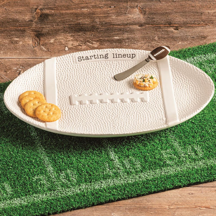 White oval platter with food on a green football field mat