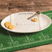 White oval platter with food on a green football field mat