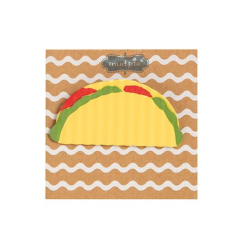 Taco-shaped toy on a wavy patterned background with 'mudpie' branding.
