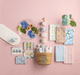 Collection of floral-themed stationery items on a pink background
