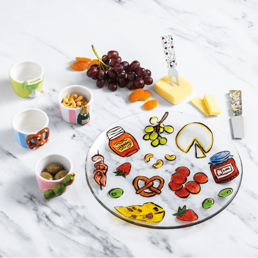 Colorful cheese board with various food items on a marble surface