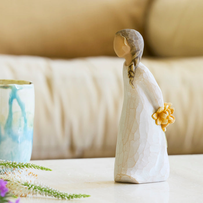 Decorative figurine of a woman holding a flower on a surface with a blurred background