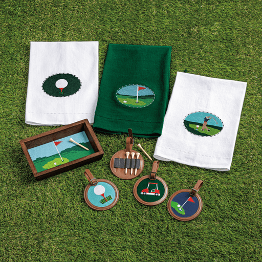 Golf-themed embroidered items including towels and coasters on a grassy background