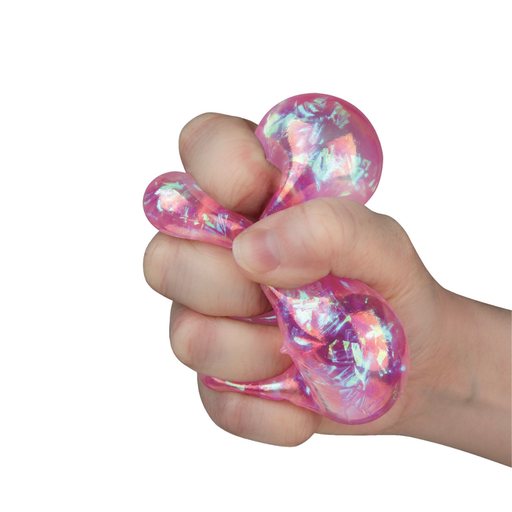 A hand squeezing a pink iridescent stress toy against a plain white background.