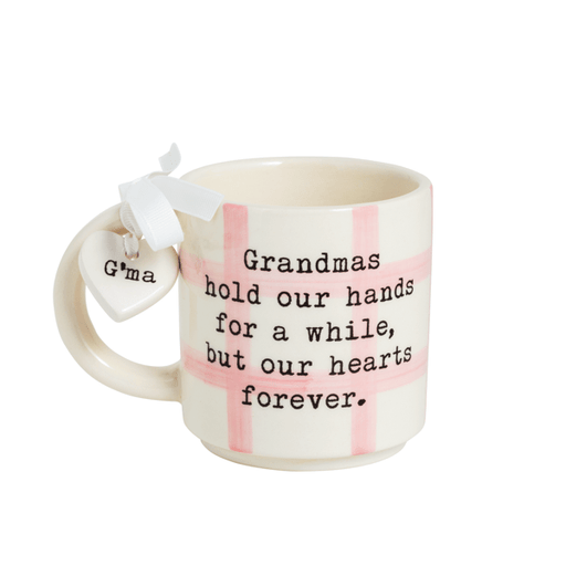 Mug with text 'Grandmas hold our hands for a while, but our hearts forever.' and a heart-shaped tag on a white background.