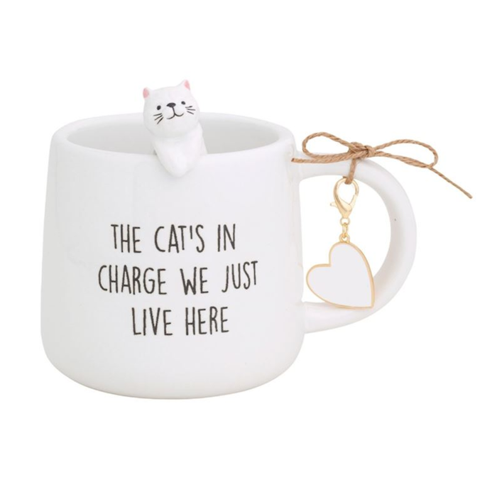 White mug with a cat design and text 'The cat's in charge we just live here' on a white background