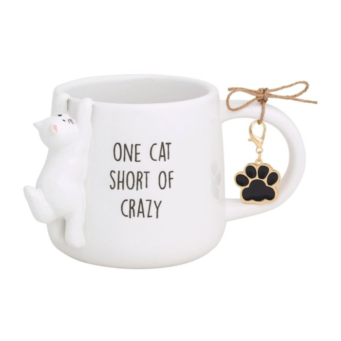 Cat-shaped mug with 'One cat short of crazy' text and paw charm on a white background