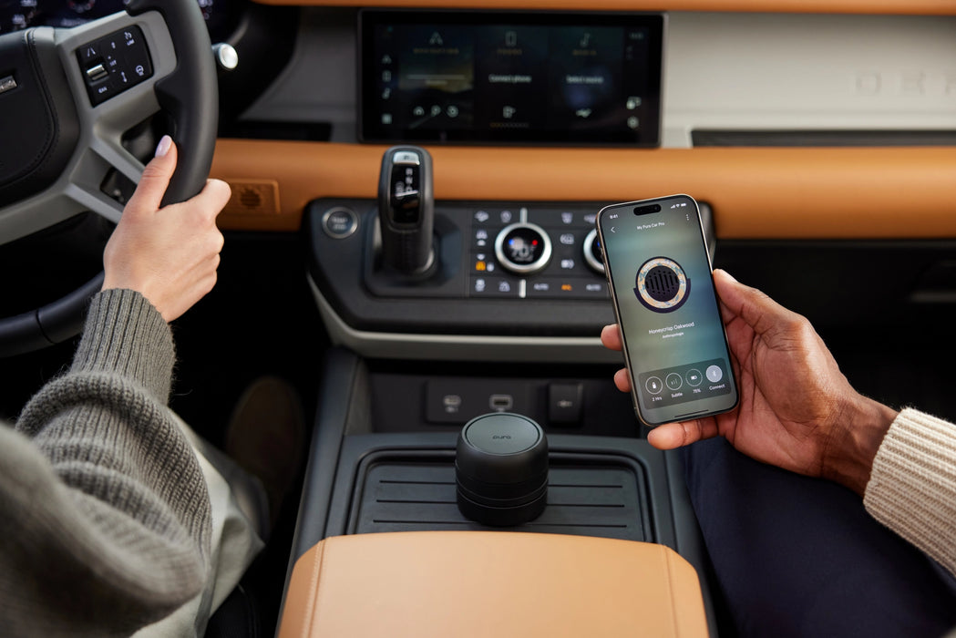 Person using a smartphone inside a vehicle with a focus on the car's interior and technology.