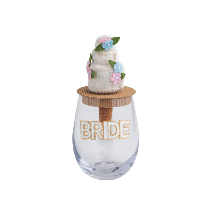 Clear glass with 'BRIDE' text, wooden base, and decorative cake on a white background