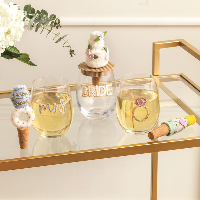 Wine glasses with 'Mrs.' and 'Bride' on a decorative table with flowers and decorative items.
