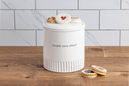 White cookie jar with text on a wooden surface and tiled wall background