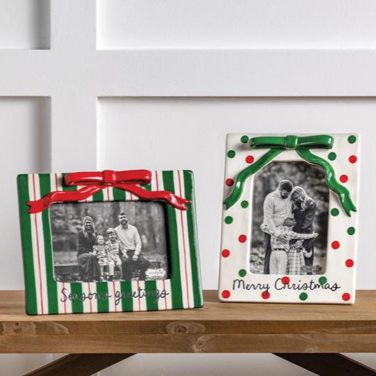 Two decorative picture frames with Christmas designs on a wooden surface.
