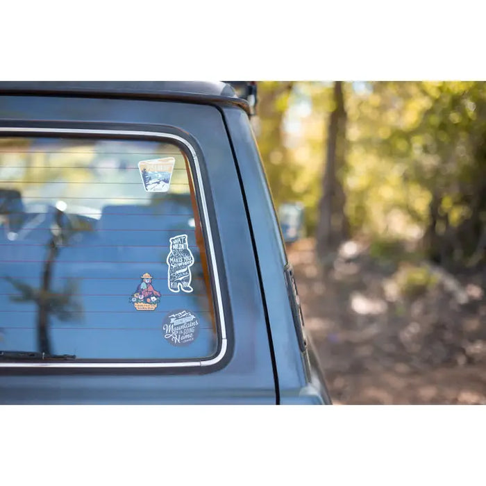 Car window with stickers and a blurred natural background