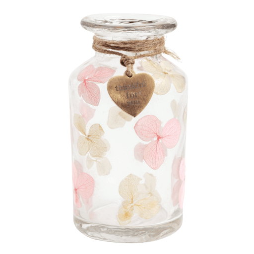 Glass jar with pink and beige flowers and a heart-shaped tag on a white background