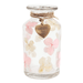 Glass jar with pink and beige flowers and a heart-shaped tag on a white background