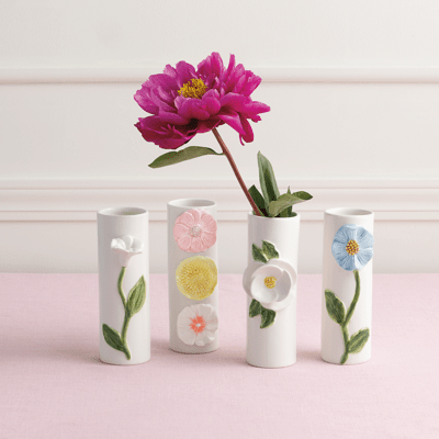 Four mugs with floral designs on a pink surface