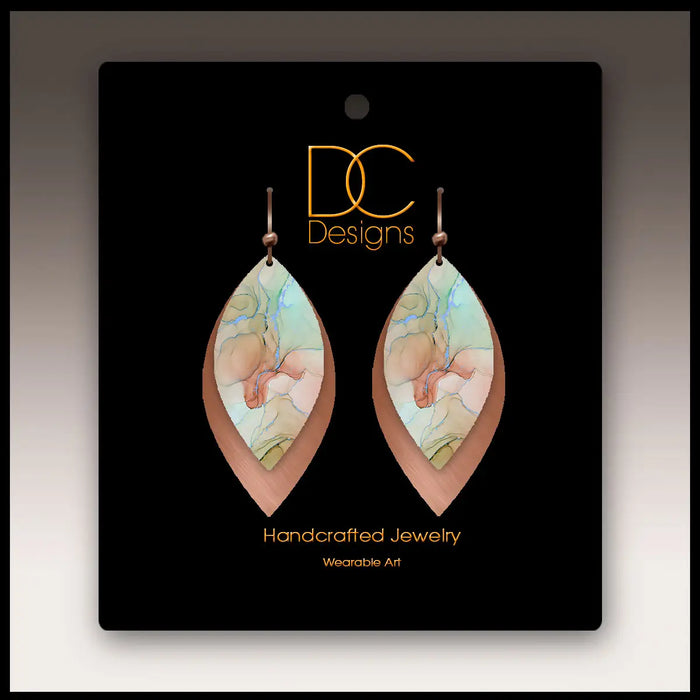 Pair of handcrafted earrings on a black card with 'DC Designs' branding.
