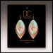 Pair of handcrafted earrings on a black card with 'DC Designs' branding.