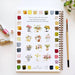 Notebook with watercolor flower designs and painting tools on a white surface