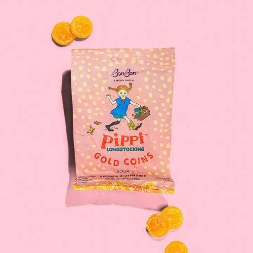 Packaging of Pippi Longstocking Gold Coins on a pink background with orange candy pieces.