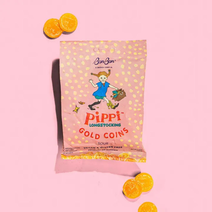 Packaging of Pippi Longstocking Gold Coins on a pink background with orange candy pieces.