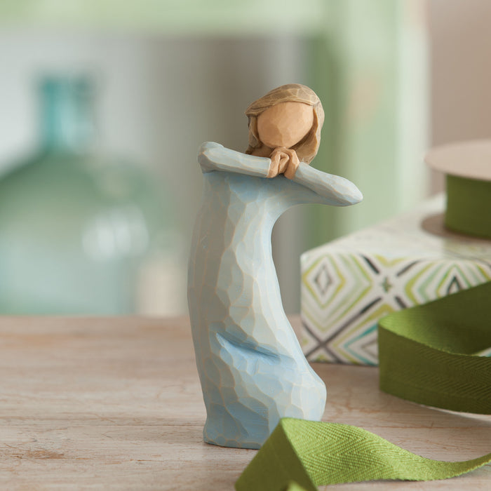 Wooden figurine of a woman embracing a wave on a wooden surface with a blurred background