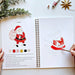 Open book with a drawing of Santa Claus and paint swatches, surrounded by Christmas decorations.