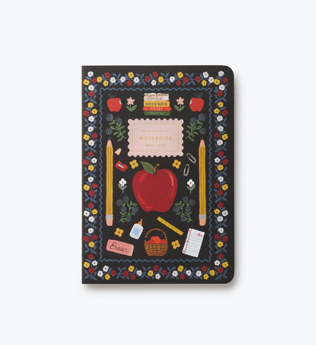 A hardcover notebook with a black cover decorated with a colorful school-themed illustration, including an apple, pencils, flowers, and a notebook, shown on a light gray background.