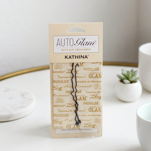 Kathina Auto Glam air freshener packaging on a white surface with decorative elements.