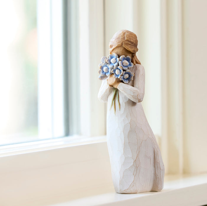 Decorative figurine of a woman holding flowers on a windowsill.