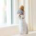 Decorative figurine of a woman holding flowers on a windowsill.