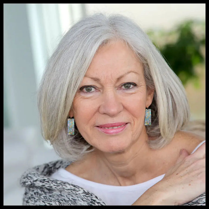 Woman with gray hair wearing earrings indoors