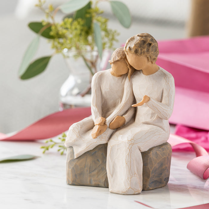 Statue of two people embracing on a rock with a blurred background