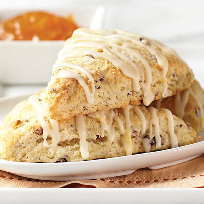 Two scones with a drizzle of icing on a white plate.