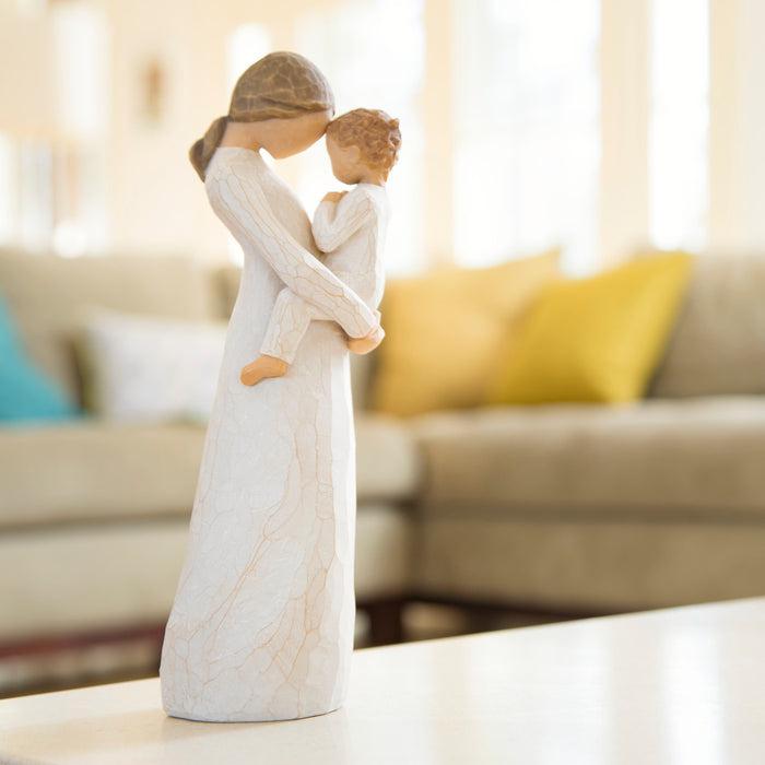 Decorative figurine of a woman holding a child on a table with a blurred living room background