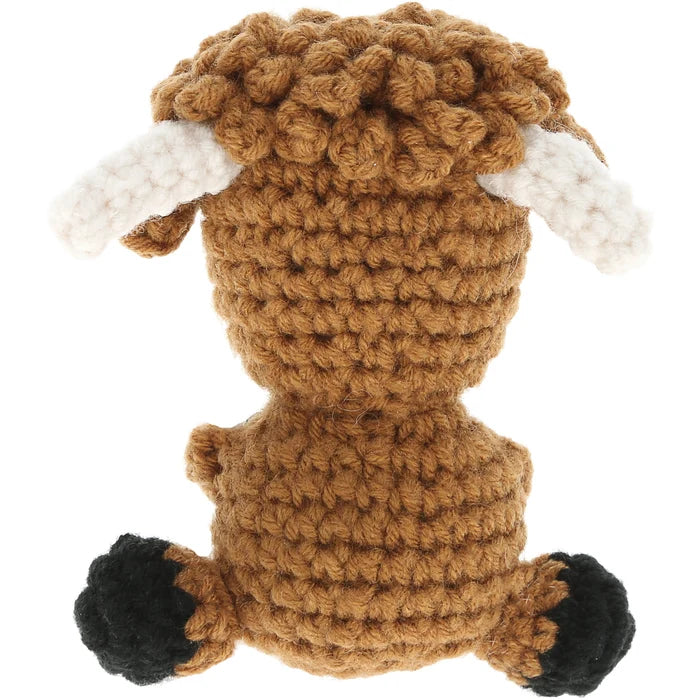 Crocheted toy cow with brown body, white antlers, and black hooves on a white background