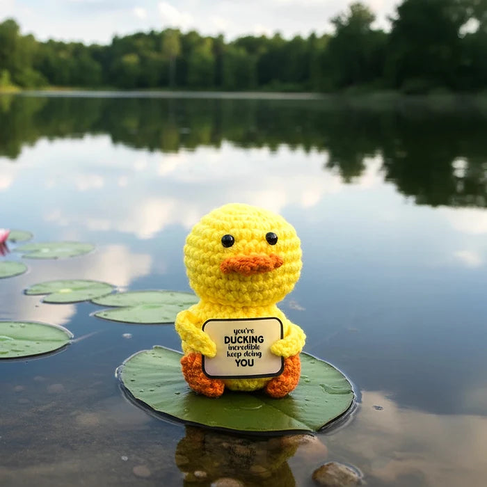 Yellow crotchet duck toy with a message on a leaf in a lake