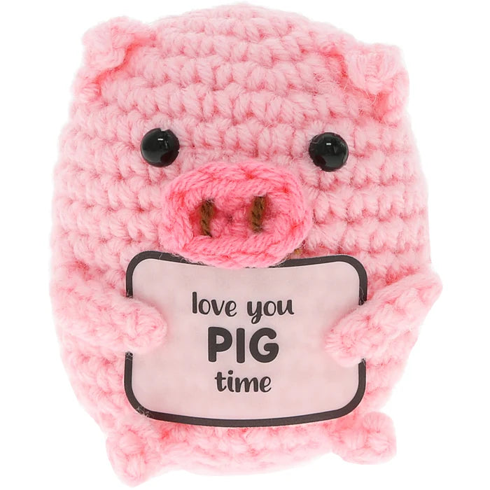A pink crocheted plush pig toy holding a sign that reads 'love you PIG time' in black text, set against a plain white background.