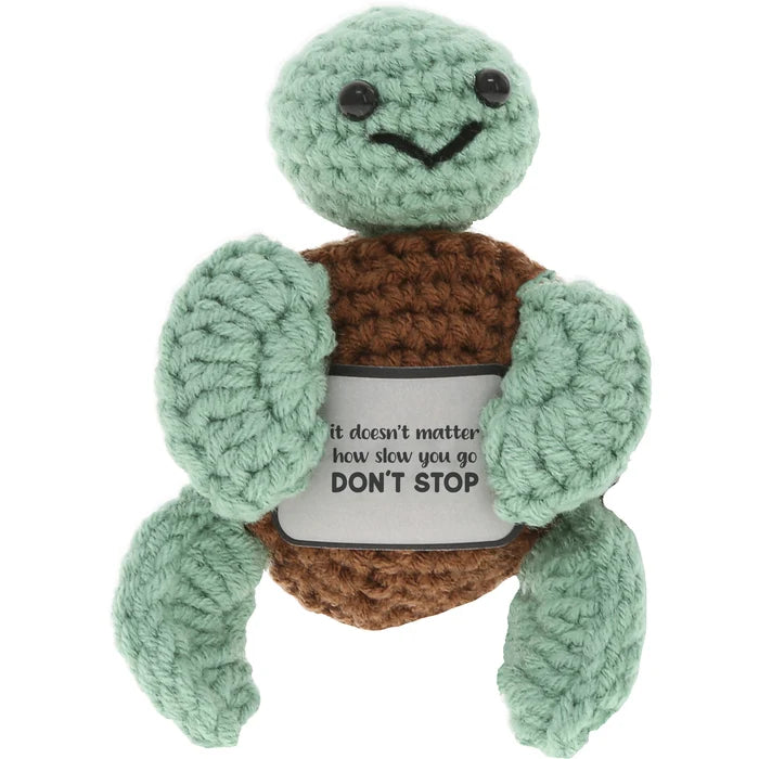 Crocheted turtle plush toy with a motivational message on a white background
