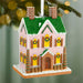 Decorative gingerbread house ornament with green roof and pink walls, hanging on a tree.