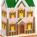 Decorative gingerbread house with pink walls, green roof, and yellow windows.