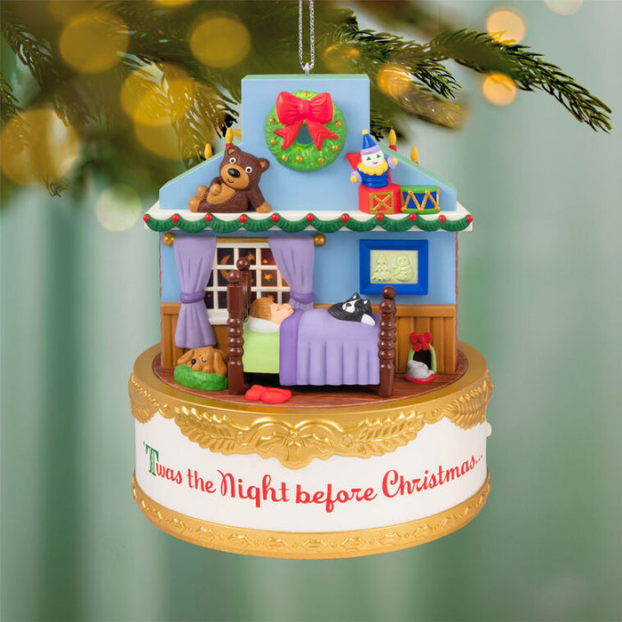 Decorative Christmas ornament with a house scene and 'Twas the Night before Christmas' text, hanging on a tree.