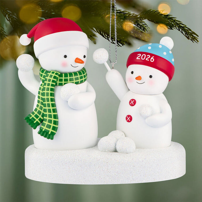 Two snowman ornaments with festive hats and scarves on a decorative base.