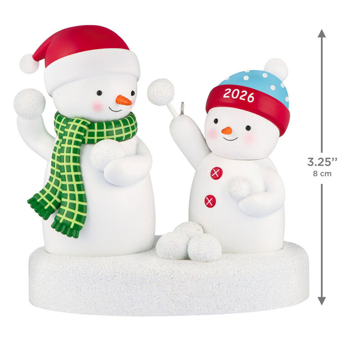 Two snowman figurines with festive hats and scarves, one marked '2026', on a white background.