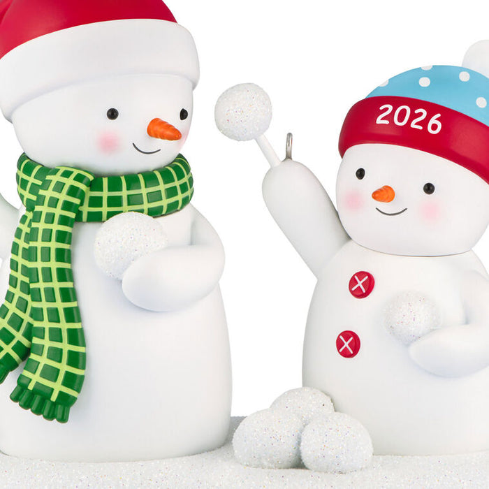 Two snowman figurines, one with a green scarf and red hat, the other with a blue and red hat labeled '2026'.