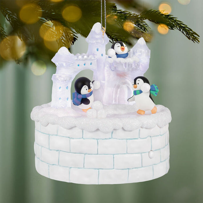 Decorative Christmas ornament with penguins and an ice castle on a blurred green background