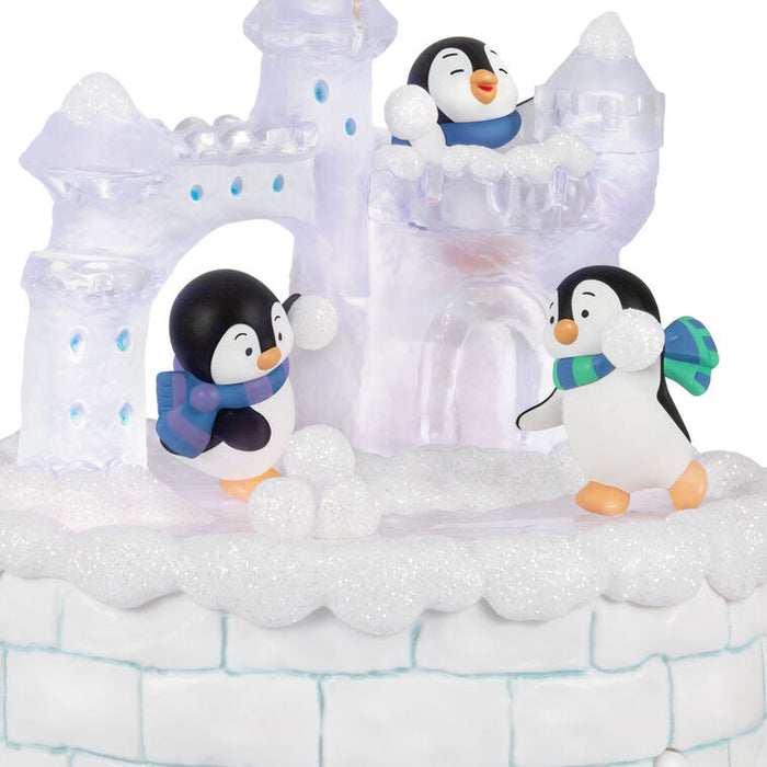 Penguin figurines with scarves on a snowy base